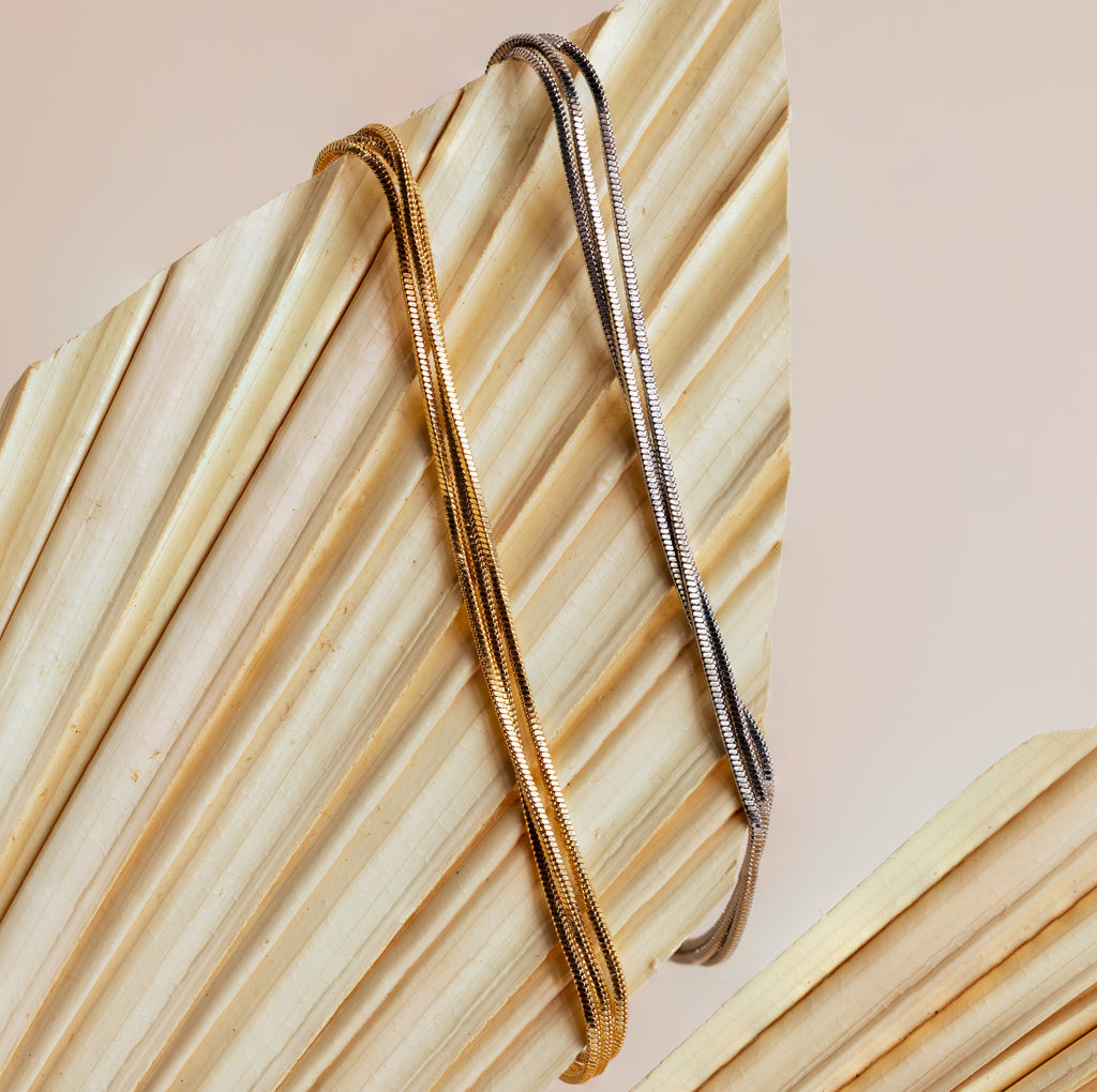 The Triple Snake Chain Bracelet in White Gold, displayed on a dried palm leaf—ideal for a minimal jewelry vibe or adding elegance to your layered look.