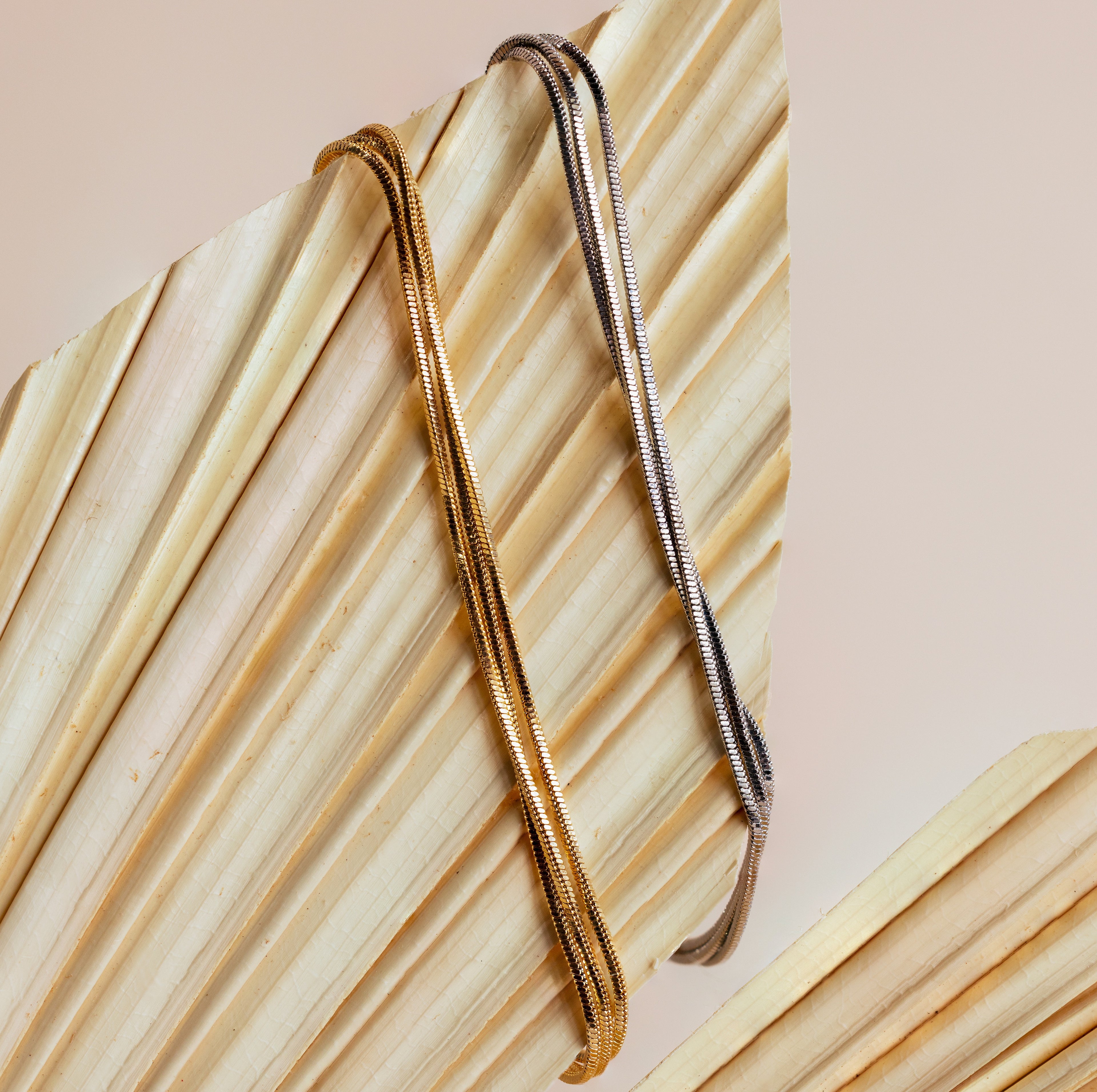The Triple Snake Chain Bracelet in White Gold, displayed on a dried palm leaf—ideal for a minimal jewelry vibe or adding elegance to your layered look.
