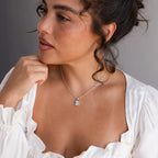 A woman in a white blouse wears the Pearl Initial Tag Necklace with a customizable chain—an elegant silver accessory and a perfect Christmas gift.