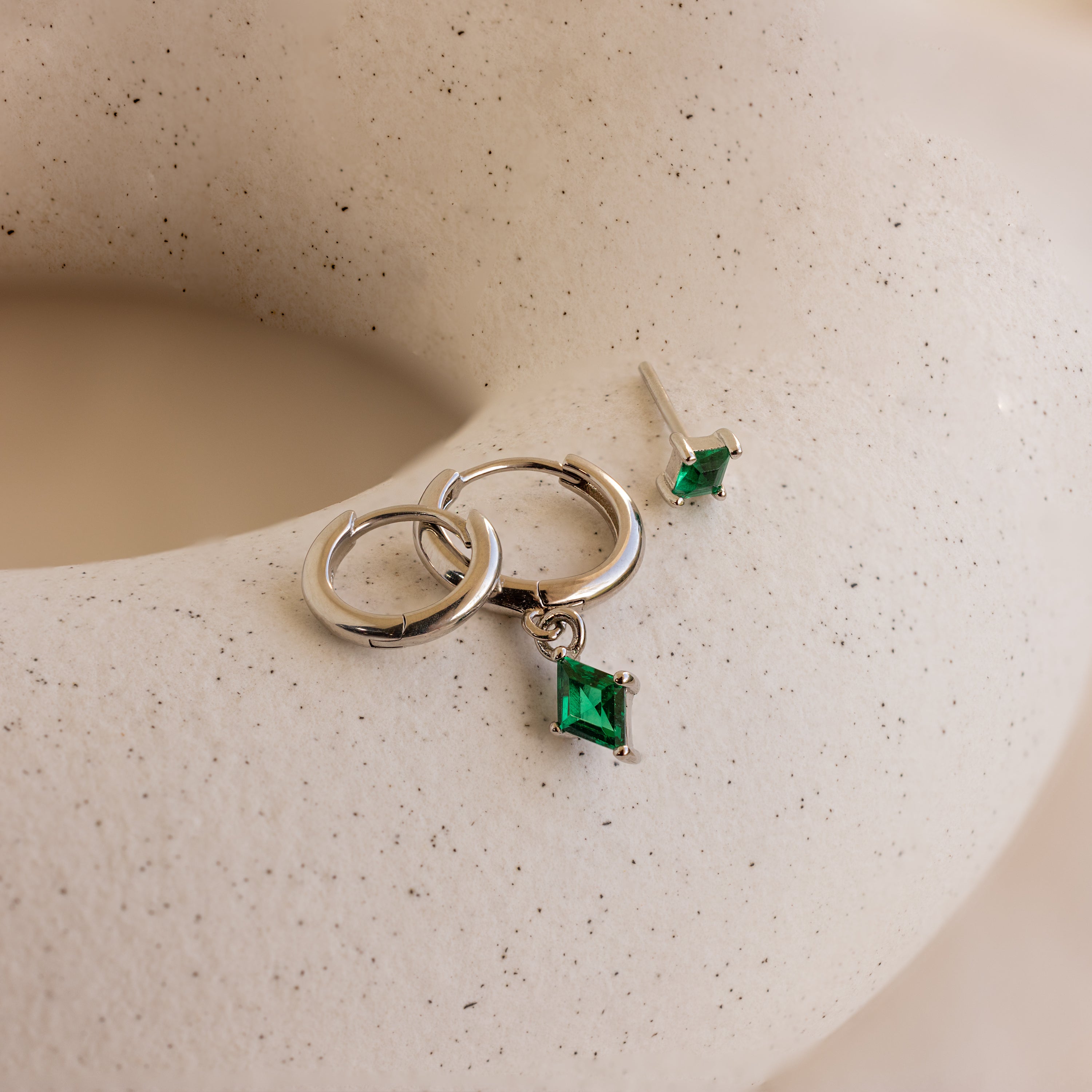 The Emerald Earrings Set is elegantly displayed on a white surface.