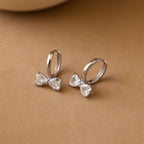 The Diamond Bow Huggies in Silver feature elegant bowtie-shaped, clear gemstone accents—perfect for a sophisticated touch.