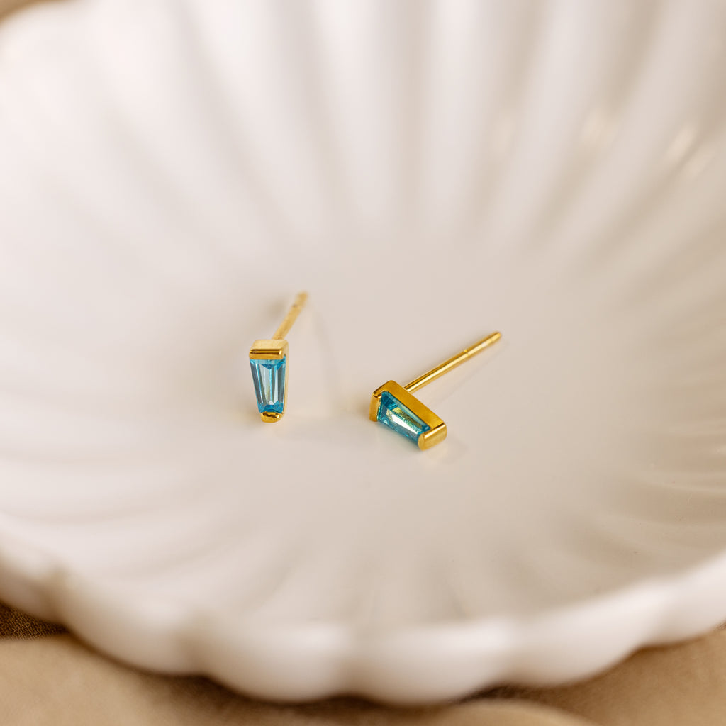 Tapered Baguette Birthstone Studs shown in a white bowl, ideal for adding gemstone jewelry elegance to any outfit.