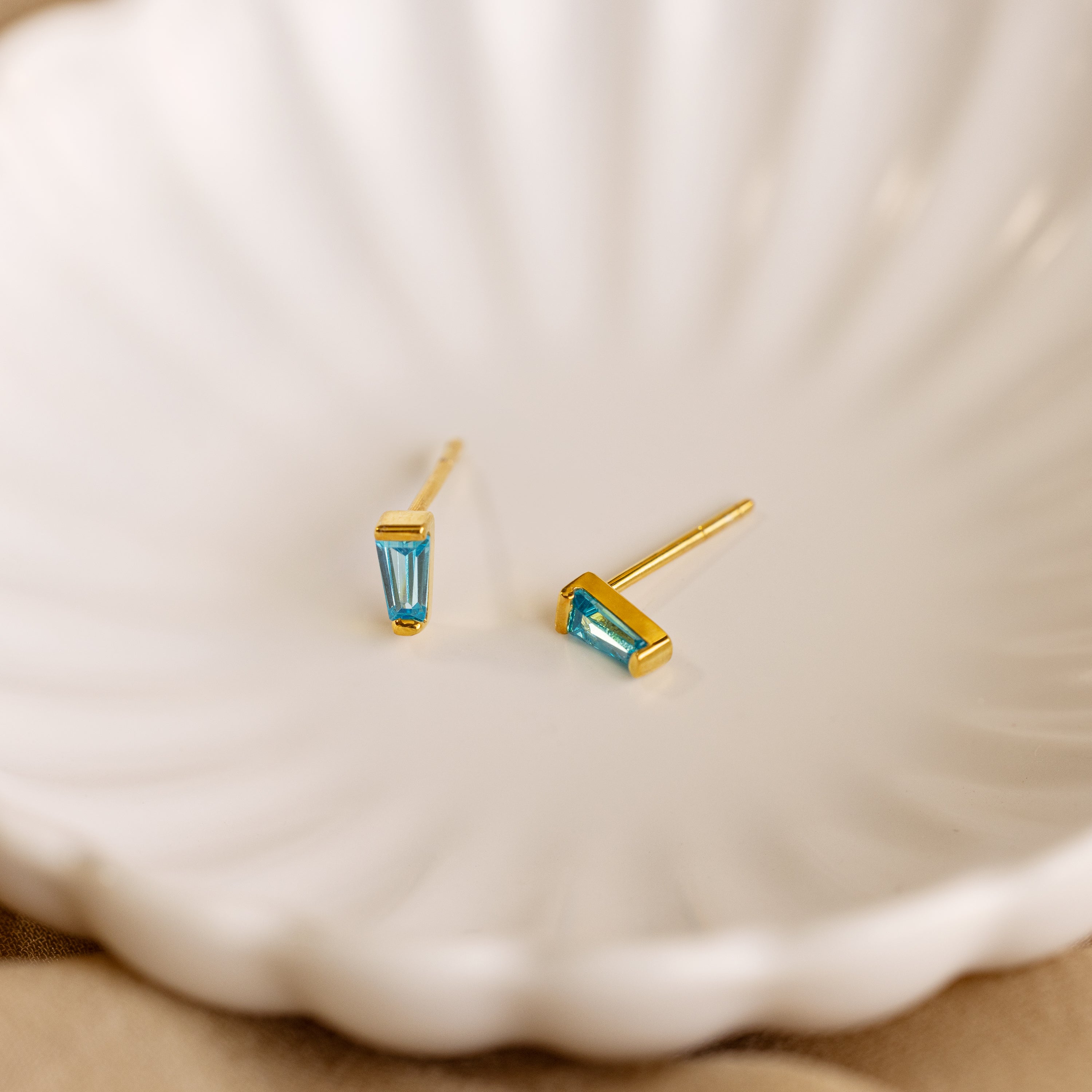 Tapered Baguette Birthstone Studs shown in a white bowl, ideal for adding gemstone jewelry elegance to any outfit.