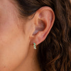 Close-up of a womans ear wearing Ombre Opal Huggies, showcasing multi-stone opal earrings with wavy brown hair visible.