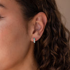 Close-up of a womans ear wearing Ombre Opal Huggies featuring three turquoise stones, with her curly brown hair visible.
