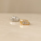 Gold and silver Art Deco Huggie earrings with baguette-cut stones displayed on a smooth marble surface.