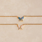 Two gold butterfly necklaces with opal wings, one in blue opal and the other in white opal, accented with small clear stones.