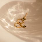 The Peridot Earrings Set in 18K Gold is displayed in a softly lit, neutral dish—ideal for stacking or as a chic cartilage earring.