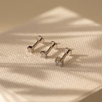 The Diamond Flatback Studs Set, a collection of dainty screw back earrings and diamond flatback studs, is elegantly displayed on a white surface.