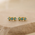 Triple Blue Zircon Huggies featuring three round blue zircon stones on a beige stone surface—perfect customizable gemstone earrings for minimalist hoop lovers.