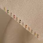 Birthstone Drop Studs, available in vibrant pairs, are displayed on a textured beige fabric—perfect for unique birth month jewelry gifts.