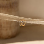 Inside Out Diamond Huggies featuring sparkling diamonds, shown on beige fabric and softly illuminated by natural light.