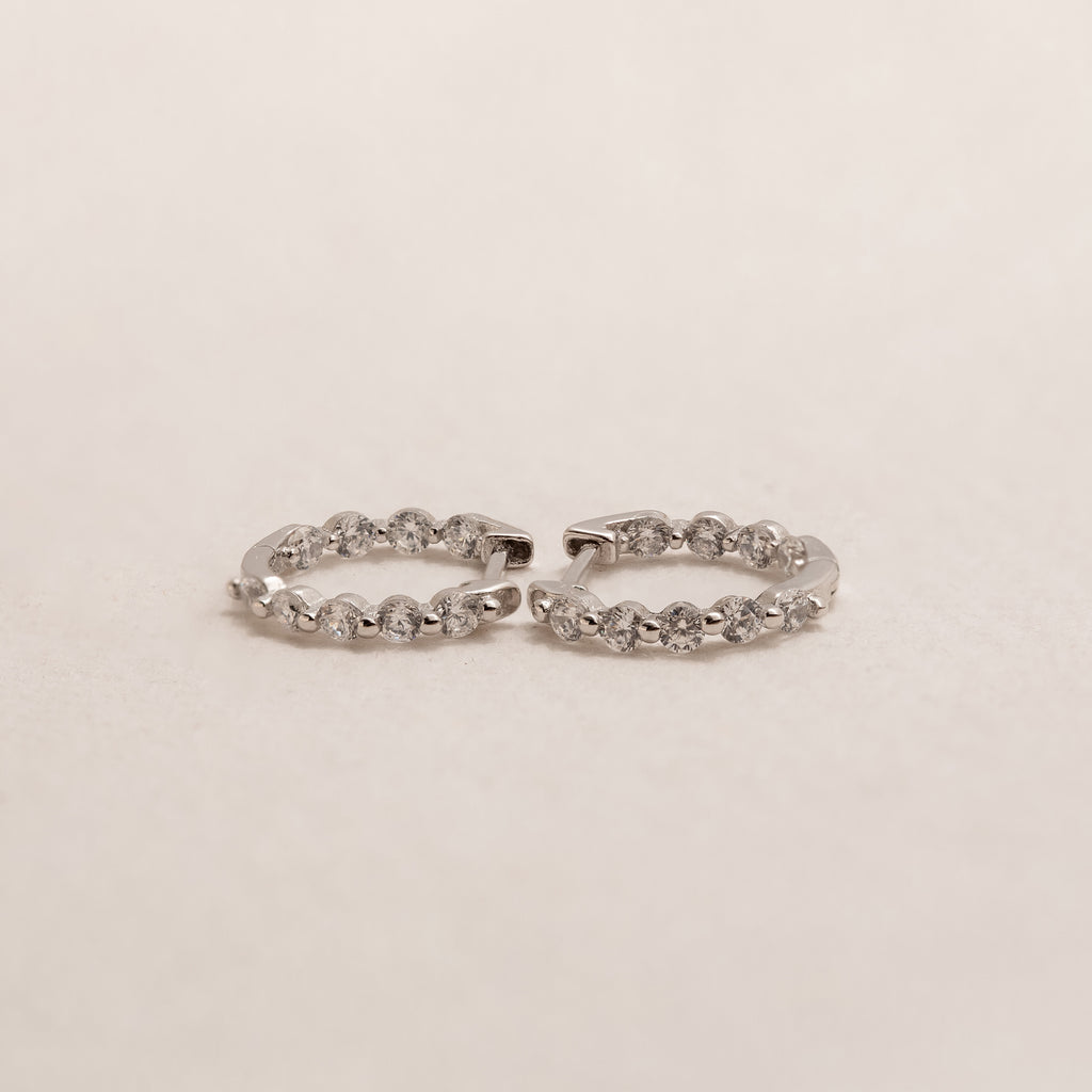 The Inside Out Diamond Huggies in Sterling Silver are hoop earrings adorned with a row of shimmering diamonds set in bright sterling silver.