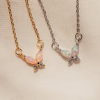 Two Pink Opal Butterfly Necklaces—one on a gold chain, one on silver—displayed on cream fabric; a charming gemstone pendant duo.