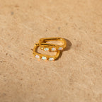 Halo Opal Hoops: minimalist gold huggie hoop earrings featuring small opal stones, shown on a light brown textured surface.