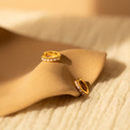 A pair of gold huggie earrings with a row of delicate pearl-like accents 