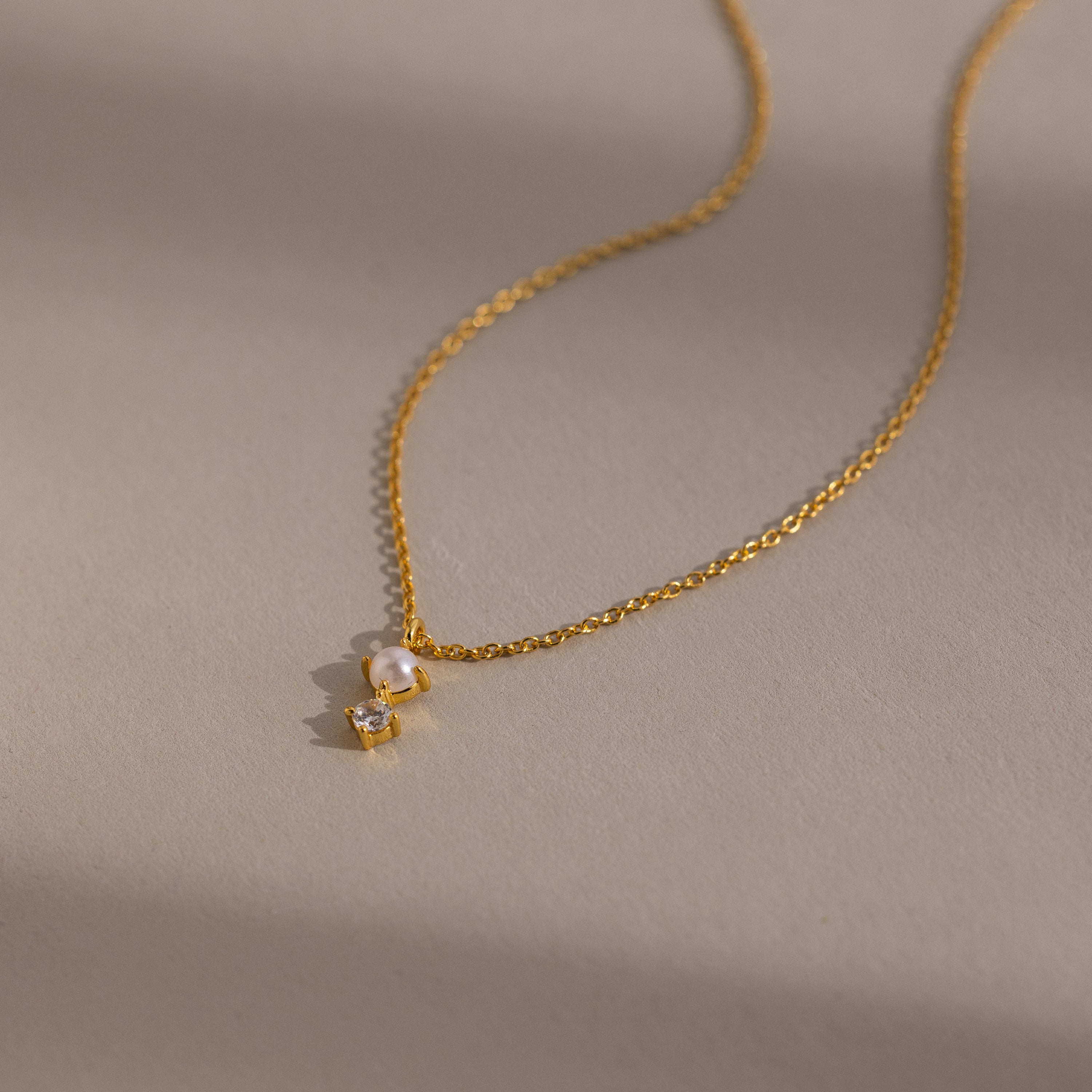 The Pearl Diamond Drop Necklace features a small pearl and clear gemstone pendant—an elegant choice for bridal jewelry.