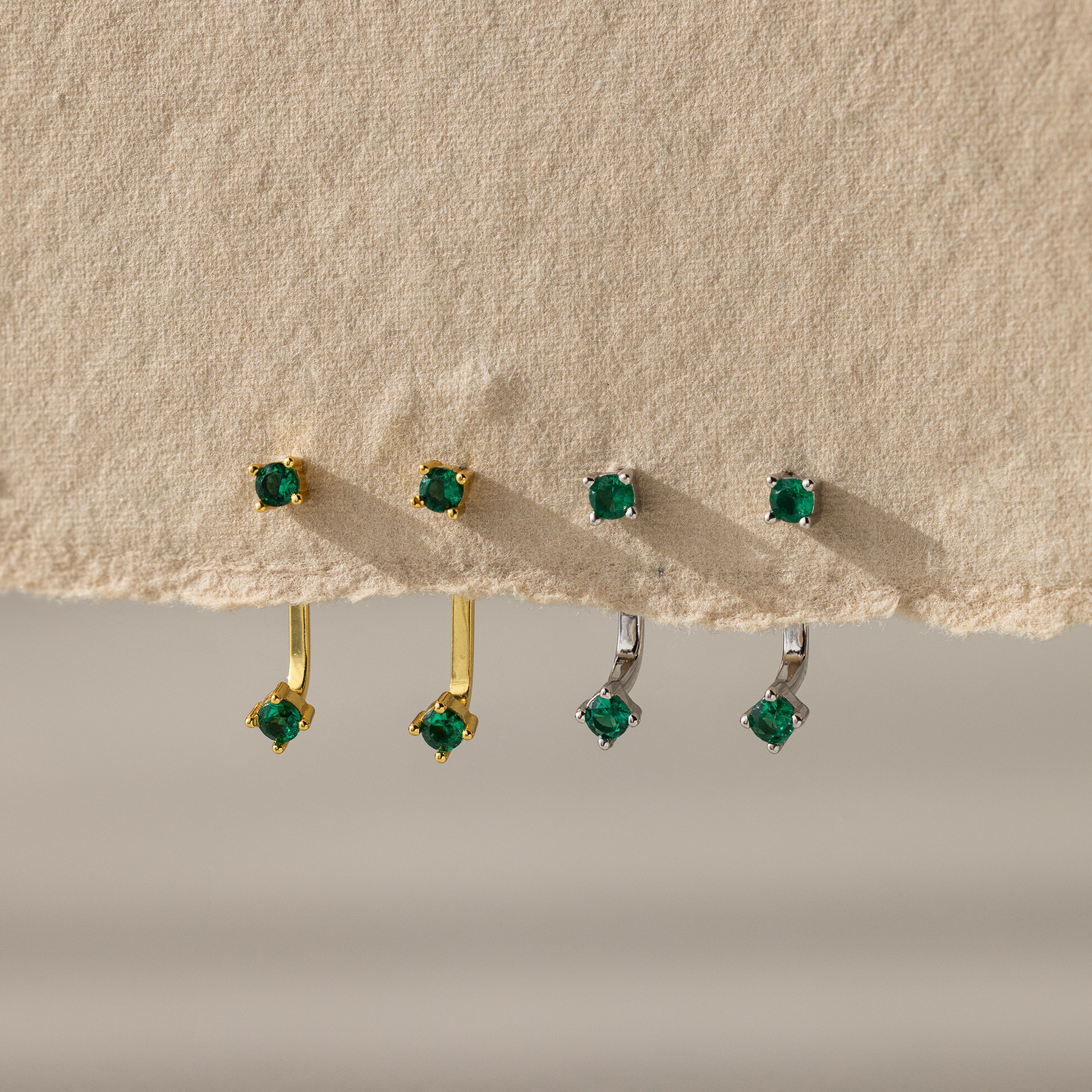 Two birthstone Emerald ear jacket  lined up to showcase contrast between gold and silver finish. 