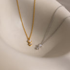 The Pearl Diamond Drop Necklace, with gold and silver pearls and crystals, is displayed on a smooth beige surface—an elegant choice for bridal jewelry.