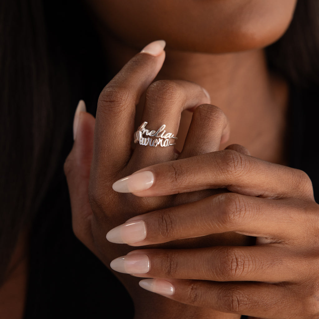 A woman’s manicured hand displays the Grace Script Name Ring in Sterling Silver, personalized with her name in an elegant script font.
