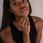 Woman in a black top touches her chin, thoughtfully gazing at the camera while wearing the Cluster Baguette Birthstone Ring in Sterling Silver.