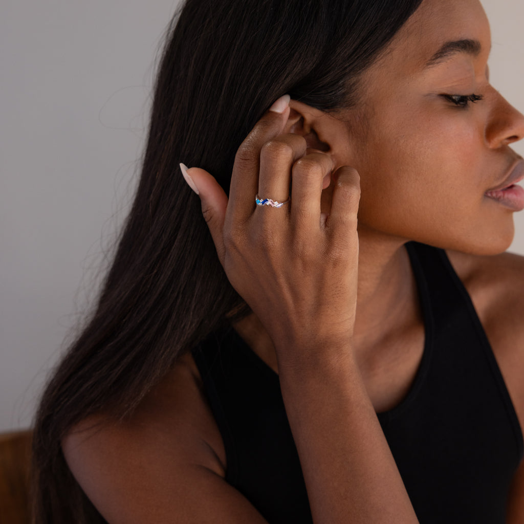 Woman in a black top touches her hair, showcasing the Cluster Baguette Birthstone Ring in Sterling Silver on her finger.