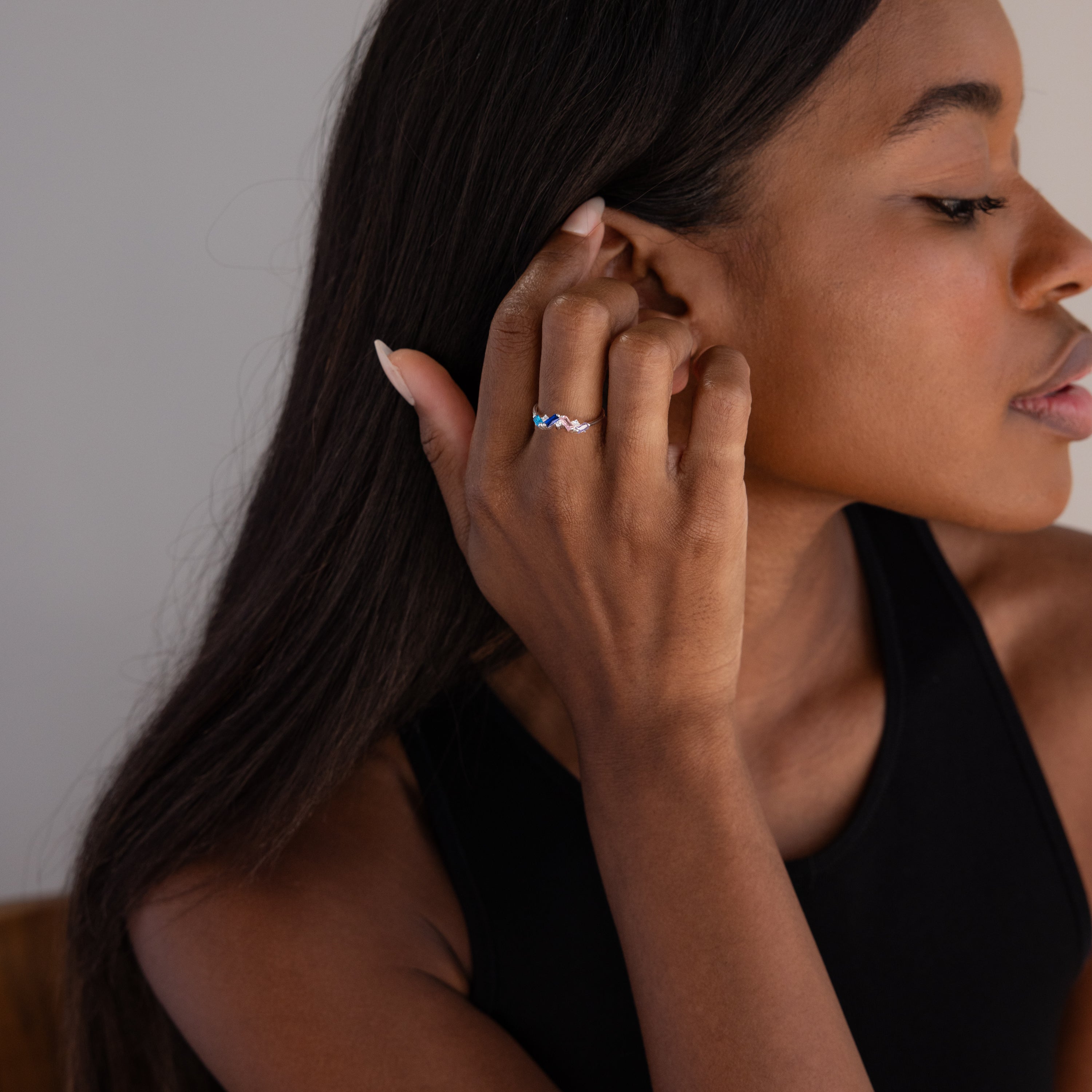 Woman in a black top touches her hair, showcasing the Cluster Baguette Birthstone Ring in Sterling Silver on her finger.