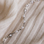 The Eternity Pearl Bracelet in Sterling Silver is displayed on a cream-colored, ribbed knit fabric, highlighting the elegant design and timeless beauty of this jewelry piece.