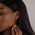 Close-up of a woman wearing silver name earrings with a neutral background