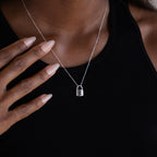 A person makes a bold fashion statement with the Padlock Necklace in Sterling Silver, featuring the letter E, paired with a sleek black top.