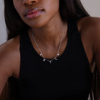 A woman wears a black tank top and a Pave Letter Necklace in Sterling Silver, customized with sparkling silver charms to spell KAYLA.