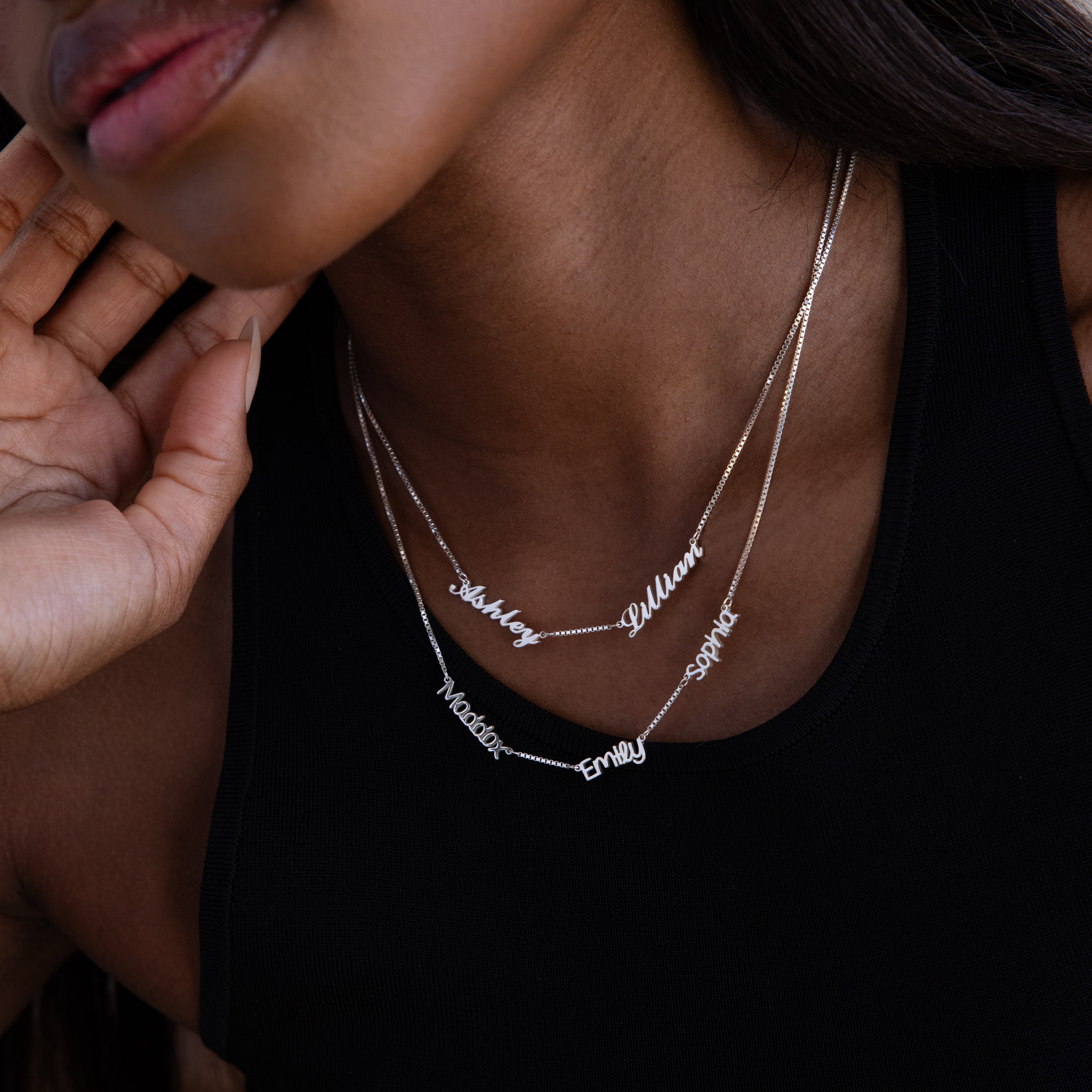 Necklace with multiple cursive name charms on a model wearing a black top.