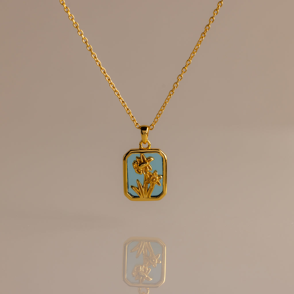 Blue Zircon Birth Flower Charm Necklace with a rectangular blue pendant featuring a floral design, displayed on a neutral background.