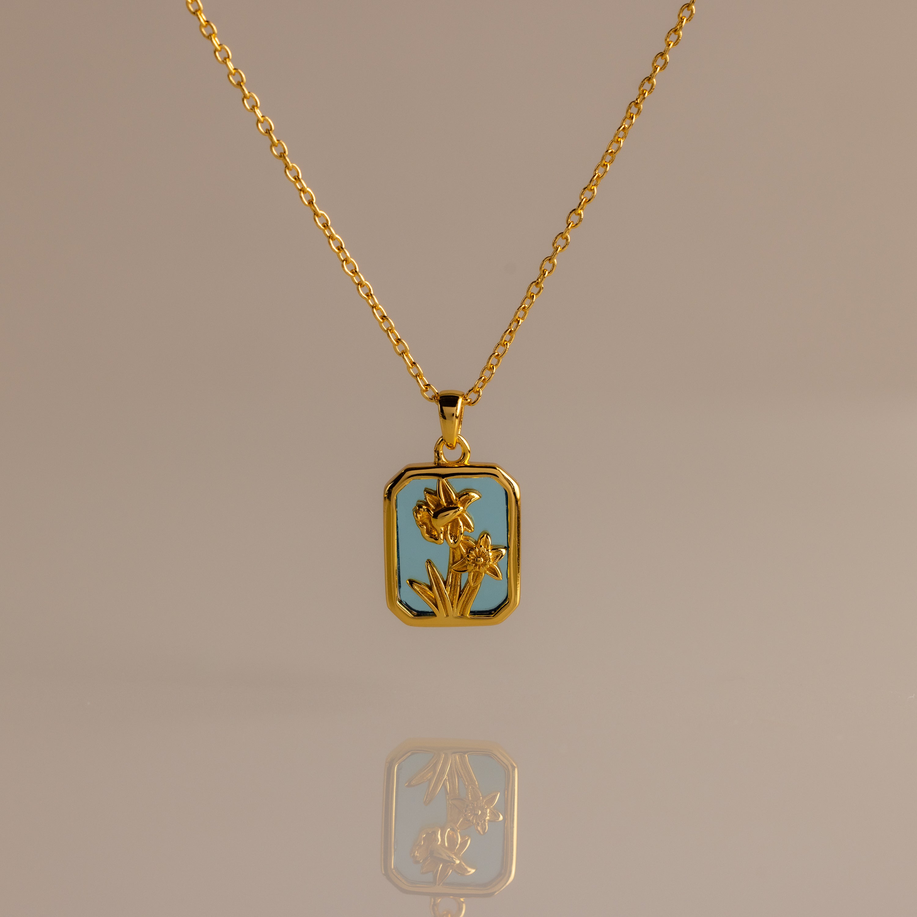 Blue Zircon Birth Flower Charm Necklace with a rectangular blue pendant featuring a floral design, displayed on a neutral background.