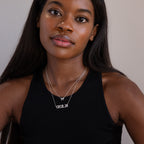 Woman with long dark hair wears a black tank top and layered silver necklaces, including a personalized necklace that spells "CECILIA" and the Pave Initial Necklace in Sterling Silver.
