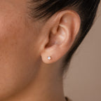 Close-up of a person's ear wearing Opal Flat Back Studs in Sterling Silver featuring a small, round light-colored opal—ideal for comfortable everyday wear.