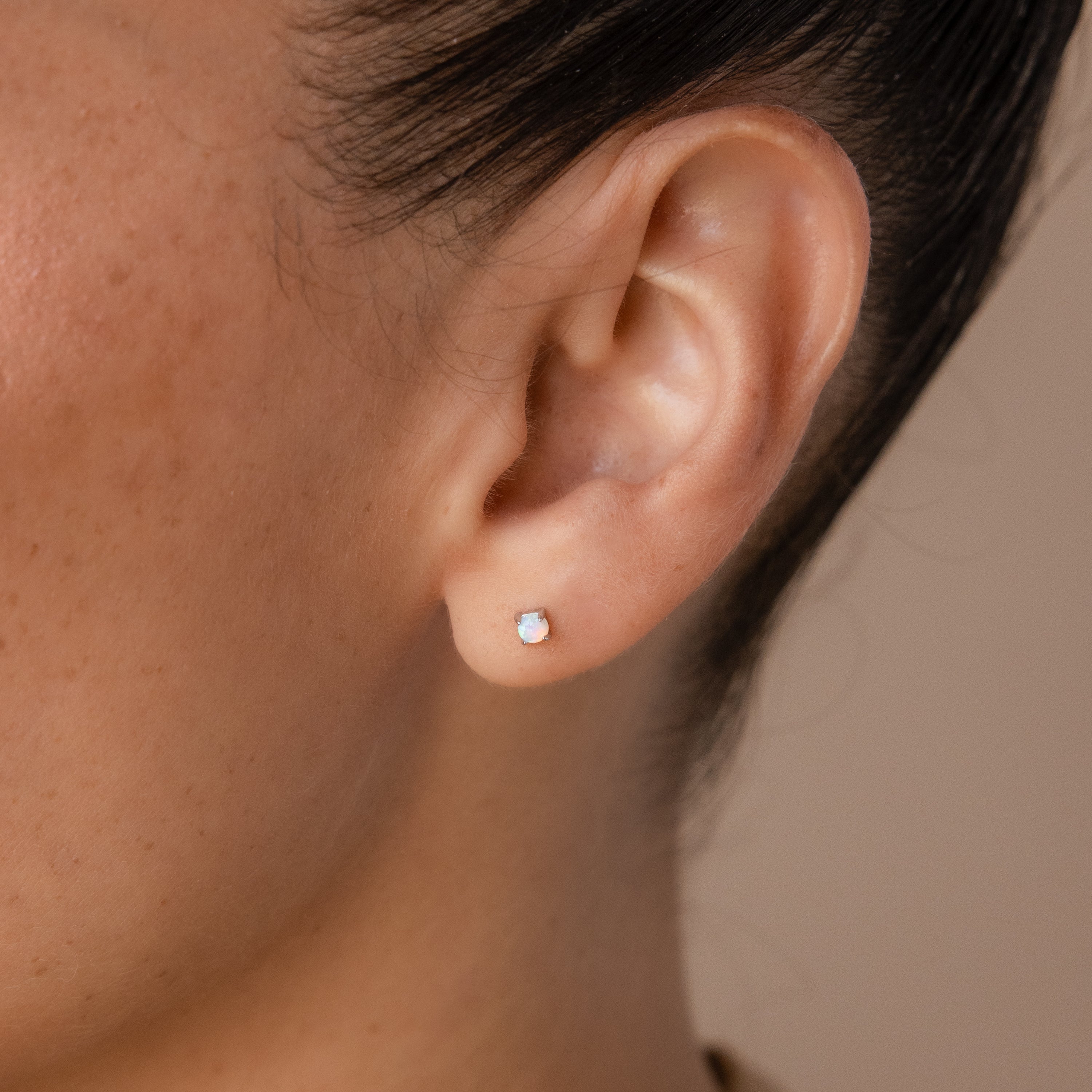 Close-up of a person's ear wearing Opal Flat Back Studs in Sterling Silver featuring a small, round light-colored opal—ideal for comfortable everyday wear.