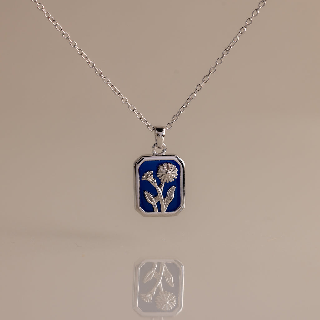 Sapphire Birth Flower Charm Necklace: Silver necklace with a blue rectangular pendant adorned with a delicate silver flower design, perfect for adding elegant style to any outfit.