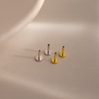 Four internally threaded flatback earring posts in silver and gold finishes, arranged on a neutral-toned surface with soft shadows.