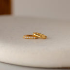 A plain gold ring and a diamond-accented ring sit on a light surface—ideal for personalization or pairing with the Multipurpose Pave Ring Lock Set in 18K Gold.