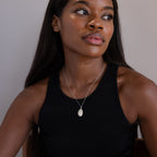 A woman in a black sleeveless top wears the Custom Fingerprint Necklace in Sterling Silver, looking off to the side.