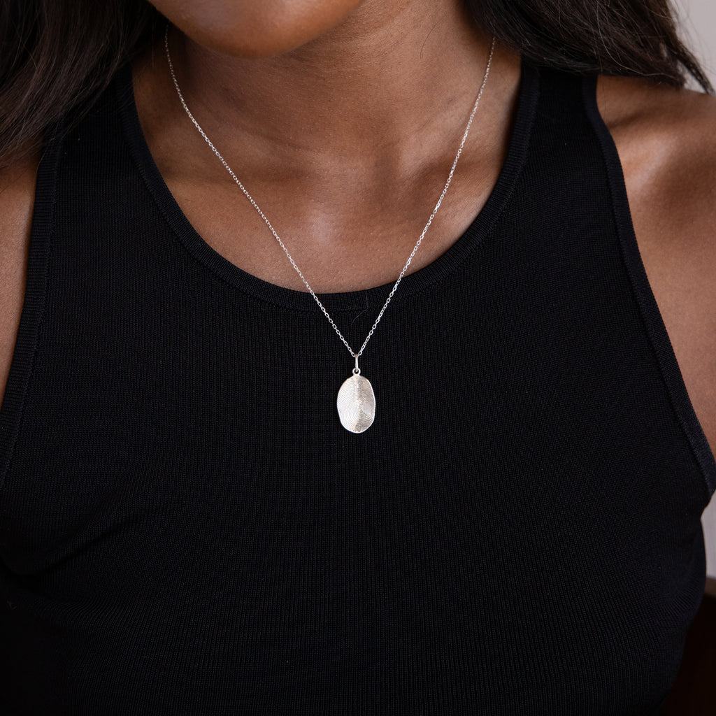 A woman wears a black tank top and a Custom Fingerprint Necklace in Sterling Silver, highlighting the personalized pendant.