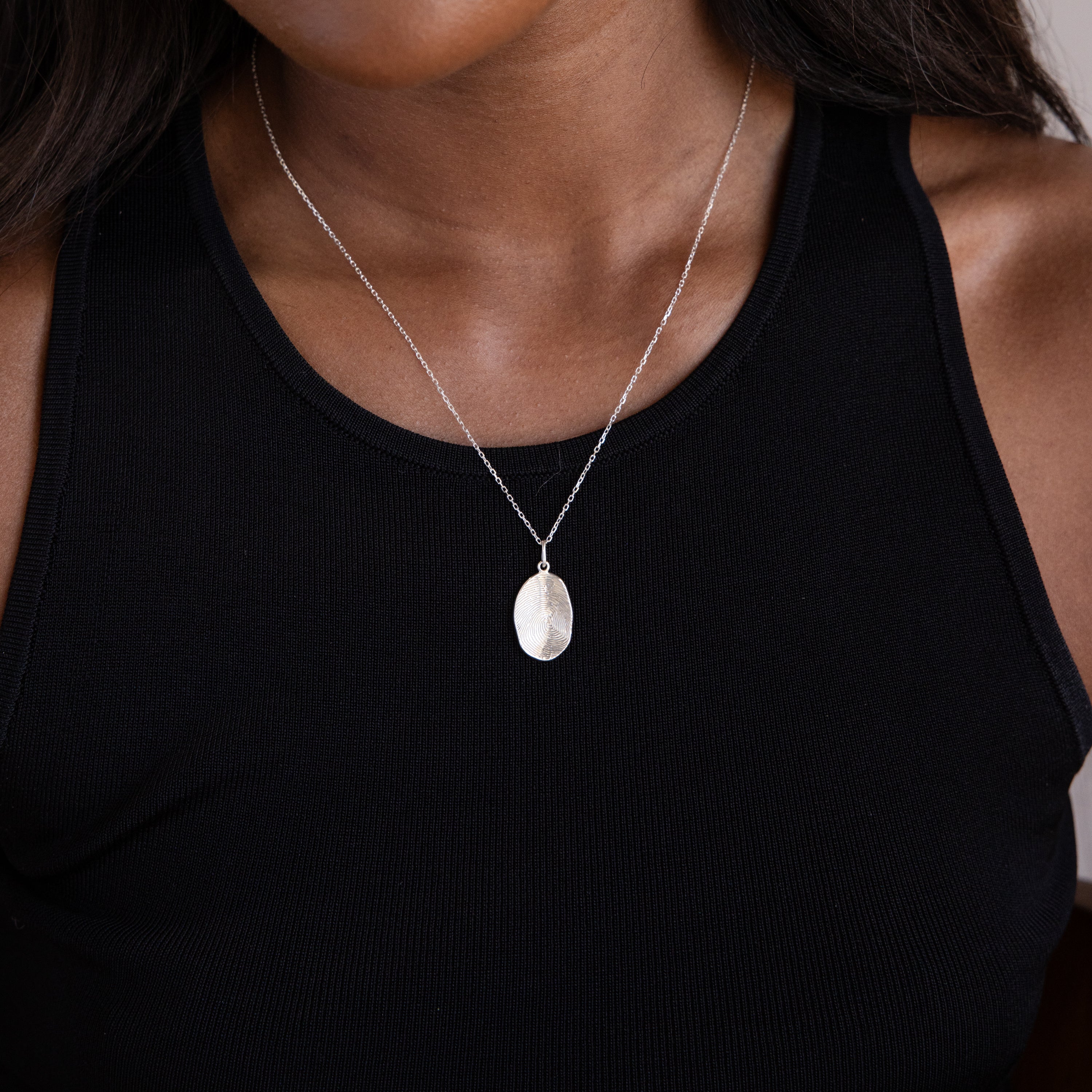 A woman wears a black tank top and a Custom Fingerprint Necklace in Sterling Silver, highlighting the personalized pendant.