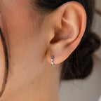 Close-up of an ear wearing Mini Diamond Sprinkle Huggies in Silver—petite, shimmering huggie hoops that catch the light with every movement.