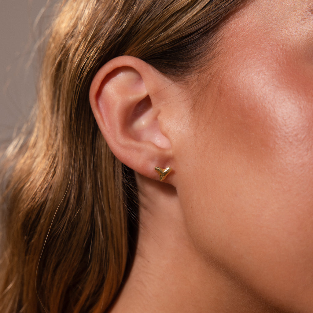 Close-up of a womans ear wearing a small, gold Shark Tooth Flatback Stud—an elegant and minimal accessory choice for the beach.