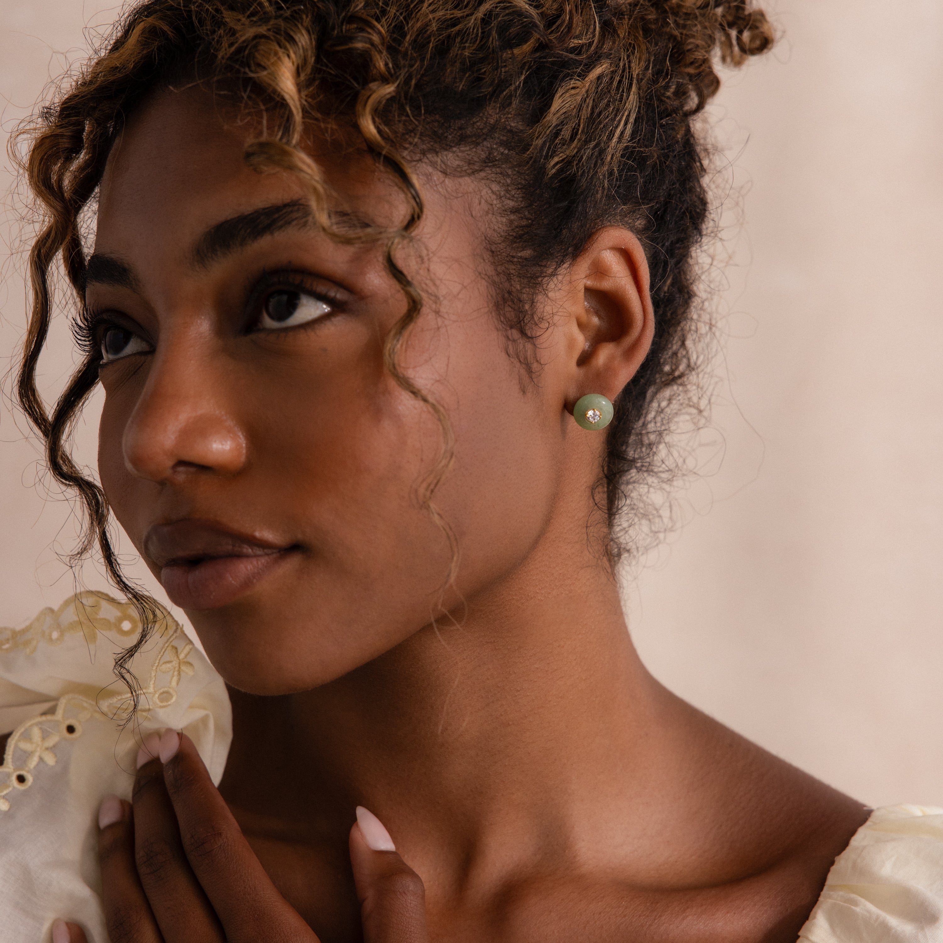 Model wearing a round green jade stud earring with a centered CZ diamond accent and gold bezel.