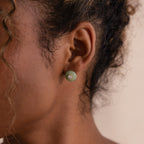 Model wearing a round green jade stud earring with a centered CZ diamond accent and gold bezel.