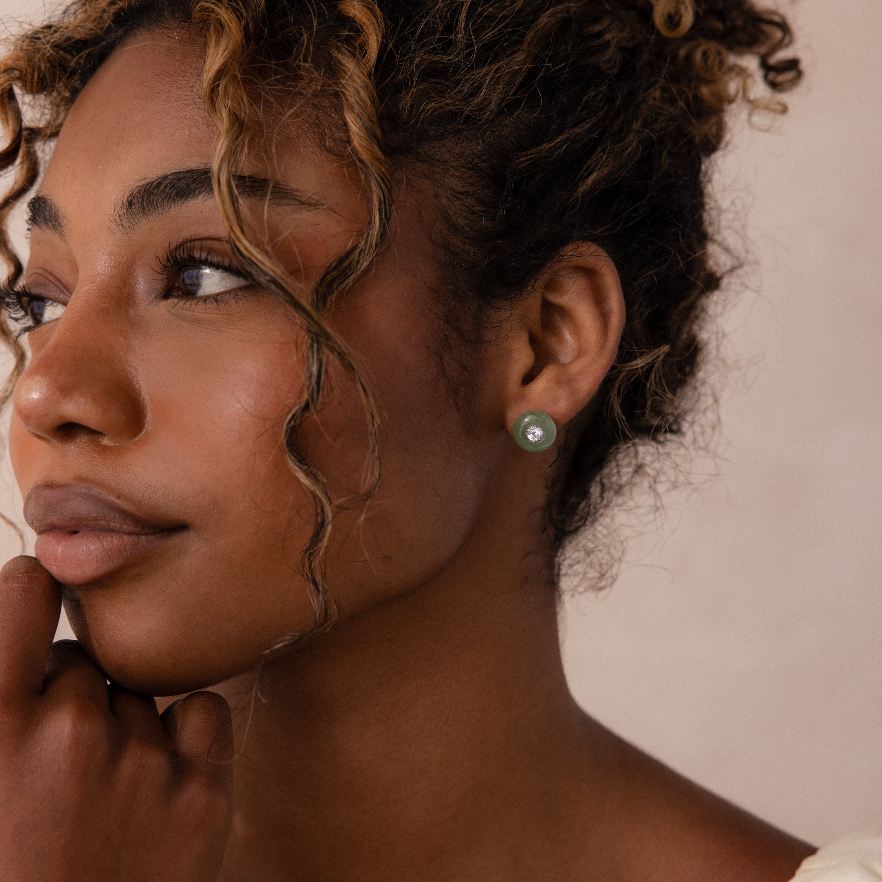 Model wearing a round green jade stud earring with a centered CZ diamond accent and silver bezel.