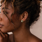 Model wearing a green jade stud earring with a centered CZ diamond, styled with multiple gold hoop and stud earrings.