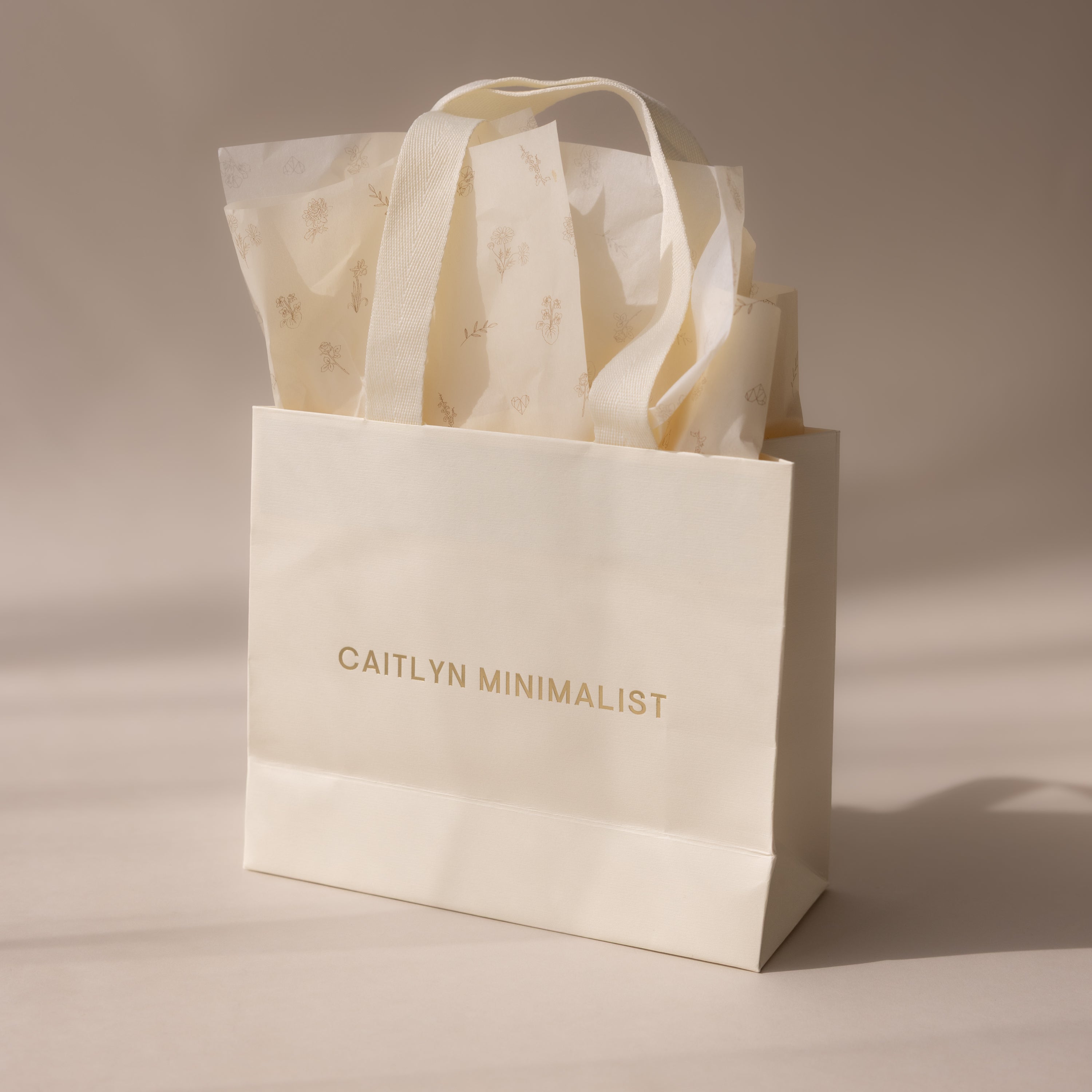 Cream-colored Gift Wrap Add-On bag with elegant text and floral tissue paper inside, providing a stylish finishing touch to your present, shown on a neutral background.